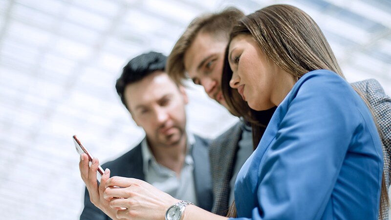 Three people looking at a phone