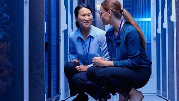 Two female engineers kneeling in a server room
