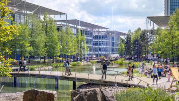A group of people walking on a bridge over a pond