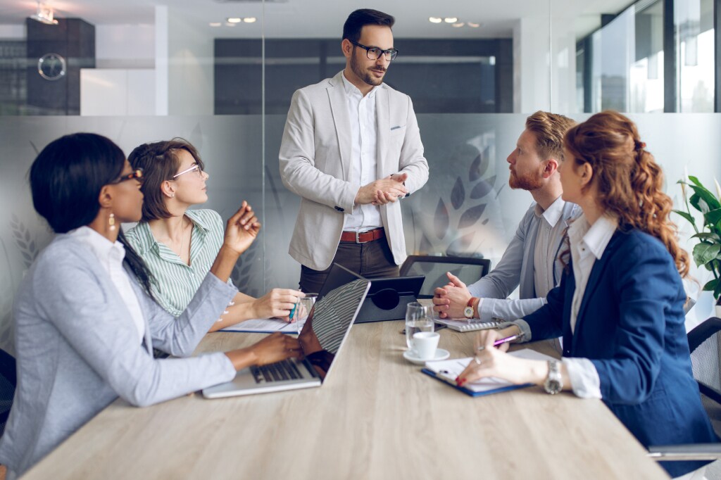 Man standing and_ talking in front of four colleagues