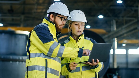 Industrial engineers hard hats discuss new project.