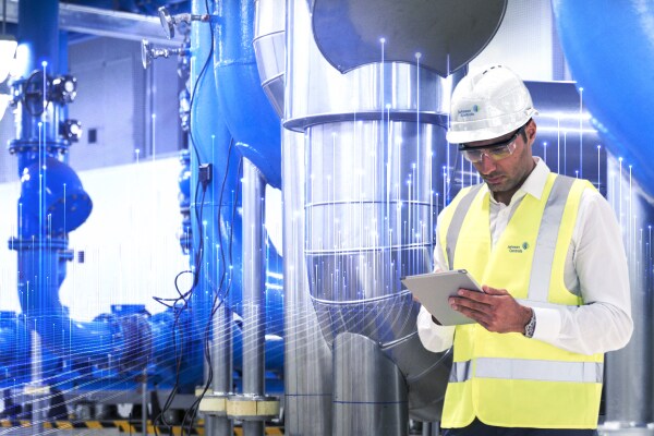 Johnson Controls technician using a tablet, overlaid with a graphic of transmission nodes in the background
