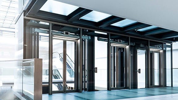 A brightly lit lobby in a building, with glass doors leading to escalators