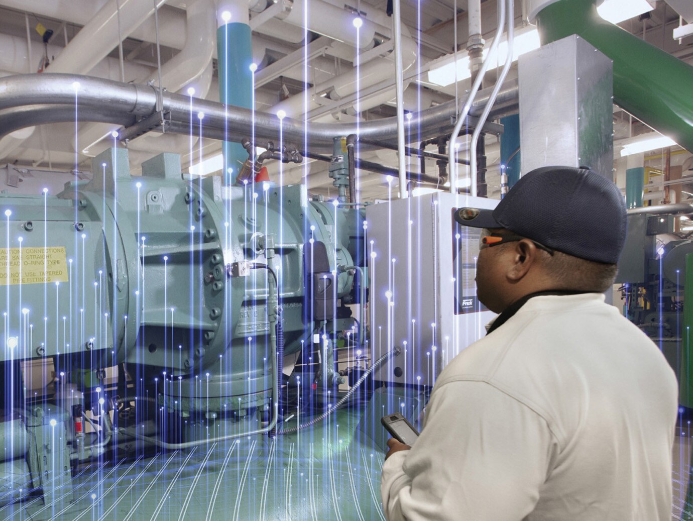 Man in safety equipment inspecting a machine with modern graphics