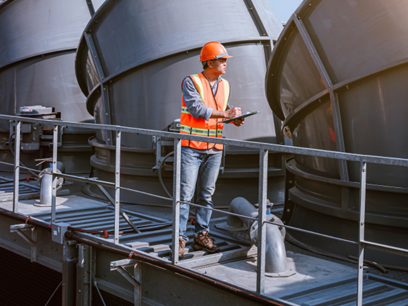 A mechanic noting something on a writing pad in an HVAC plant