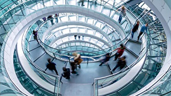 People going down a glass circular stairwell in a building