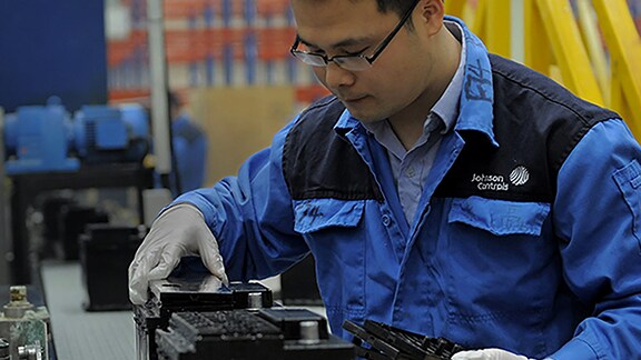 A person wearing glasses and gloves working on a machine.
