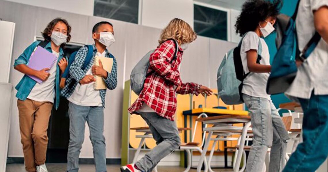 Elementary school students wearing face-masks, entering a classroom