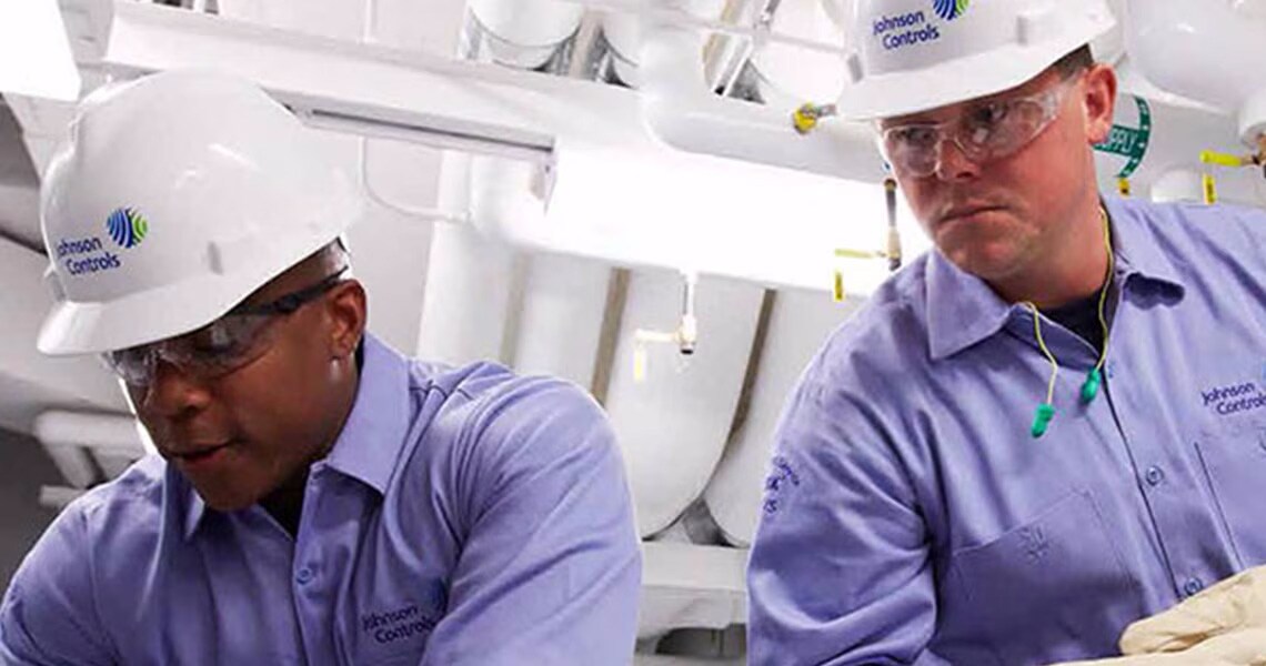 Two Johnson Controls maintenance workers wearing safety helmets