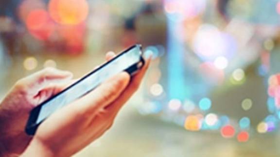 Close-up of hands using a smartphone against a bokeh background