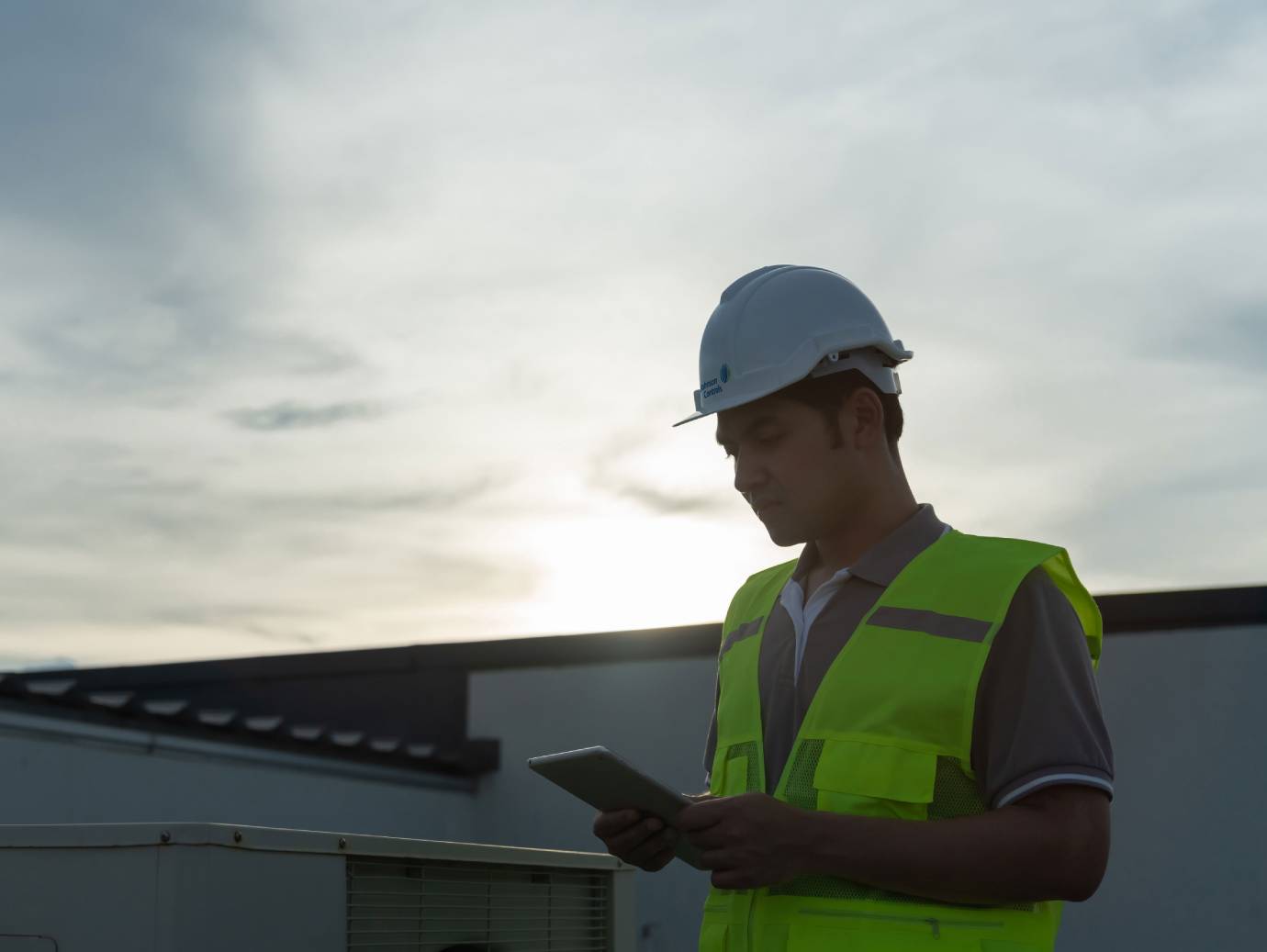 A mechanic reading a tablet on a rooftop