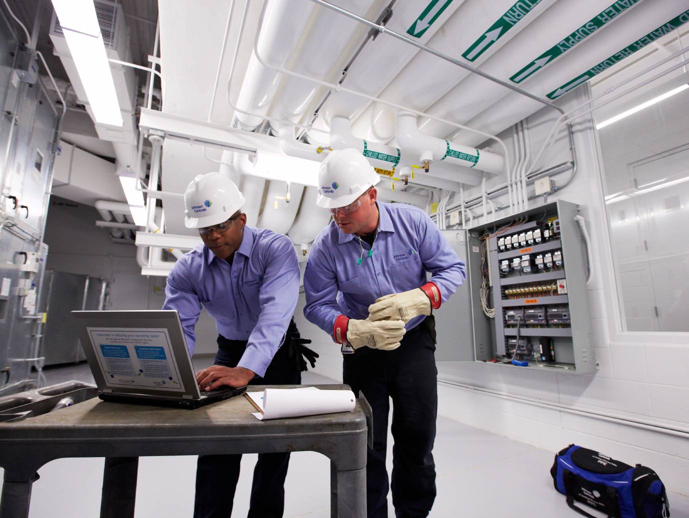 Two mechanics looking a laptop in an HVAC facility