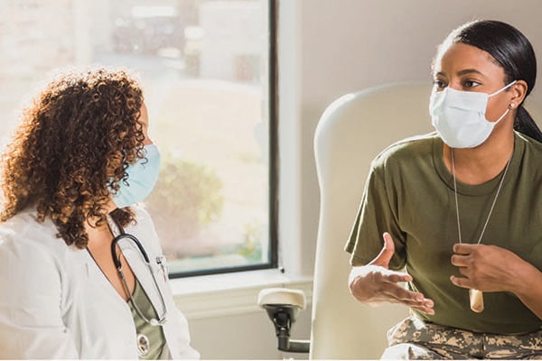 A doctor and patient wearing face masks in conversation