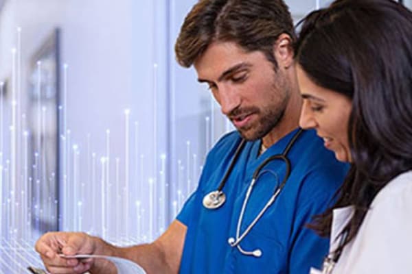 A male surgeon and a female doctor reading reports on a writing pad